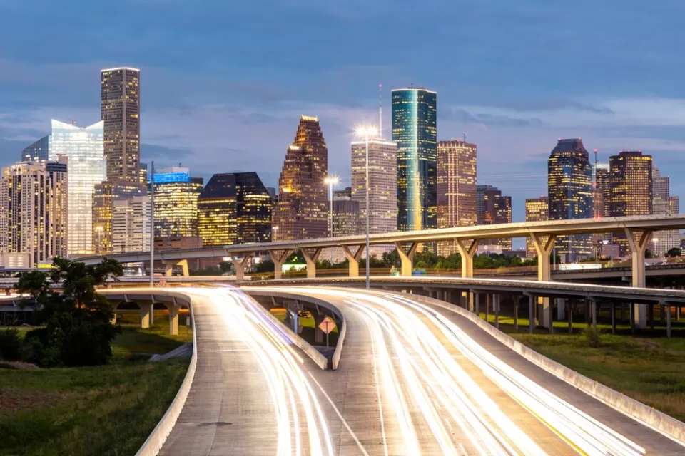 Dusk view of blurred car lights passing on freeway with Houston skyline in background
